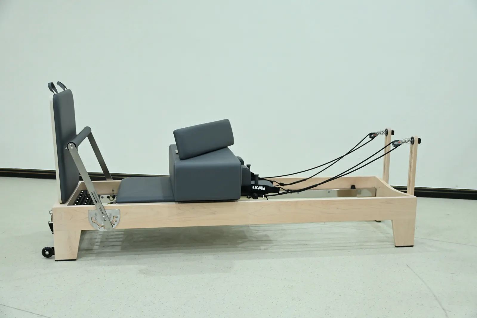 Pilates Reformer mit hellem Holzrahmen in Seitenansicht